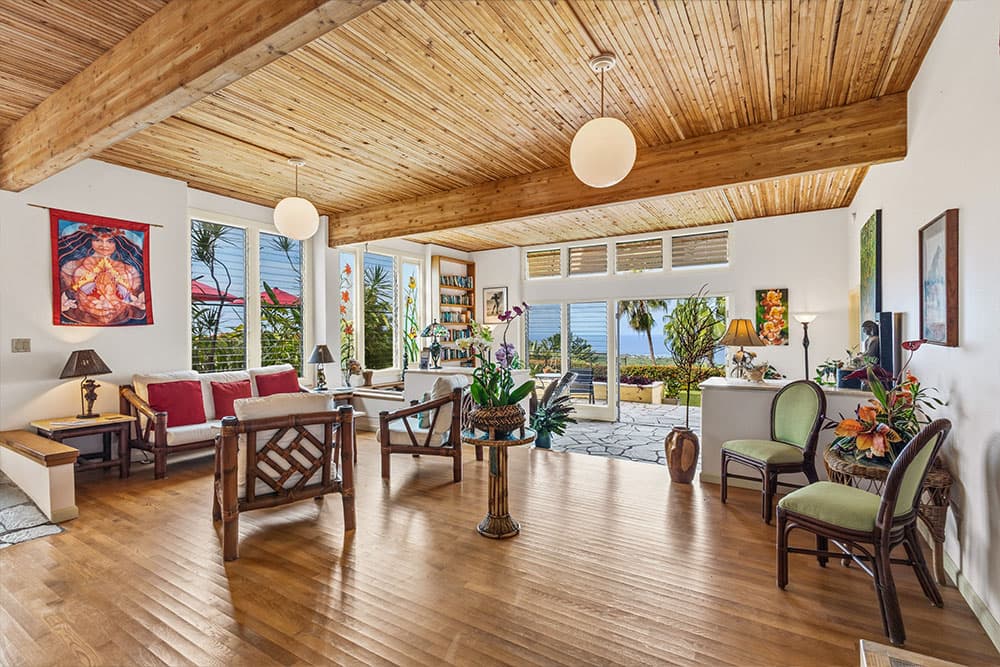 Bright, airy living room with wooden ceiling, large windows, and tropical decor.