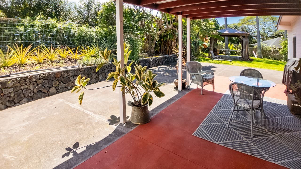 Patio area with chairs and a small table surrounded by greenery.