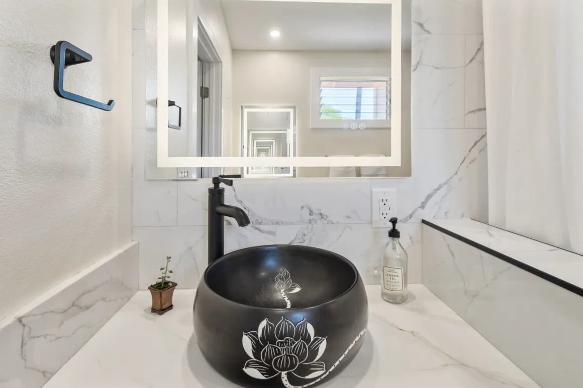 A sleek bathroom featuring a black lotus-engraved sink, modern faucet, and stylish mirror.