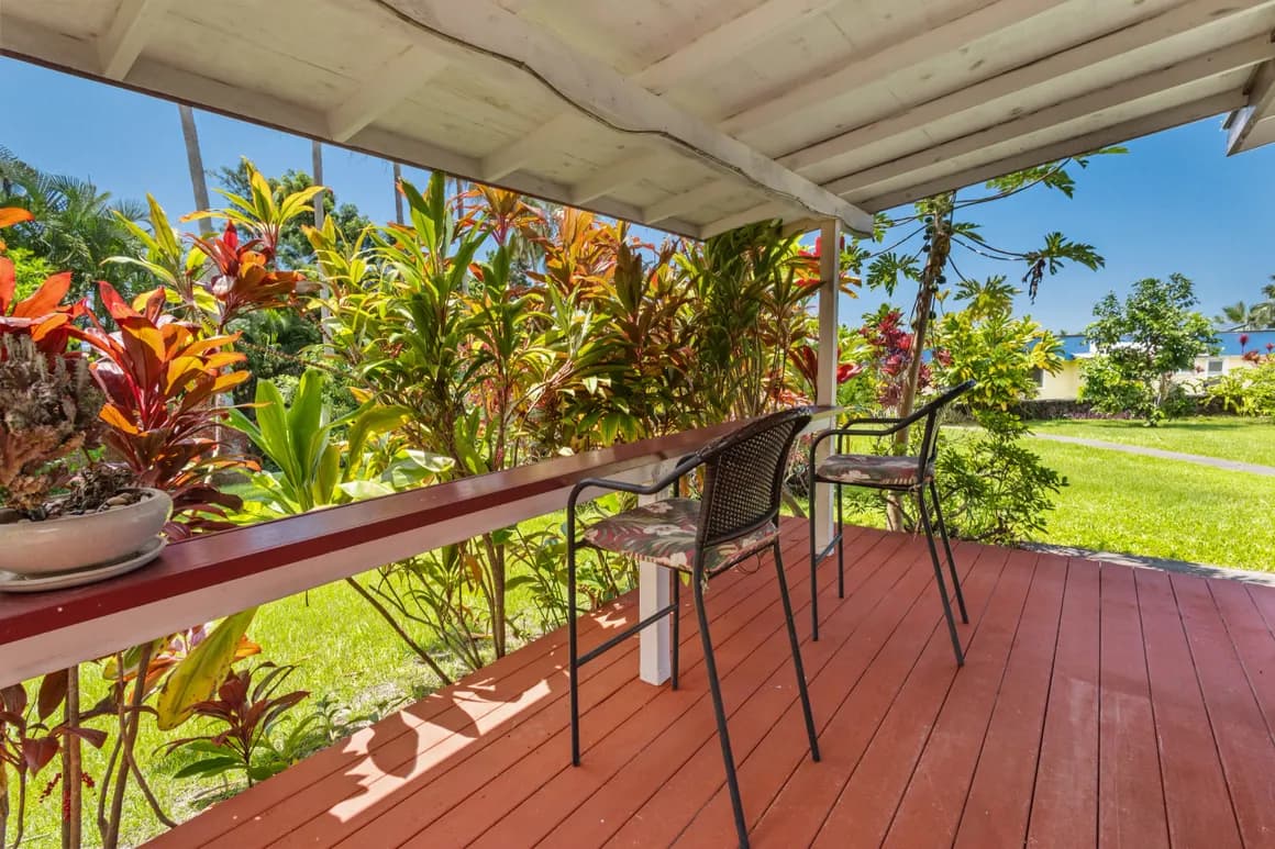 A cozy porch with two chairs, surrounded by vibrant tropical plants.