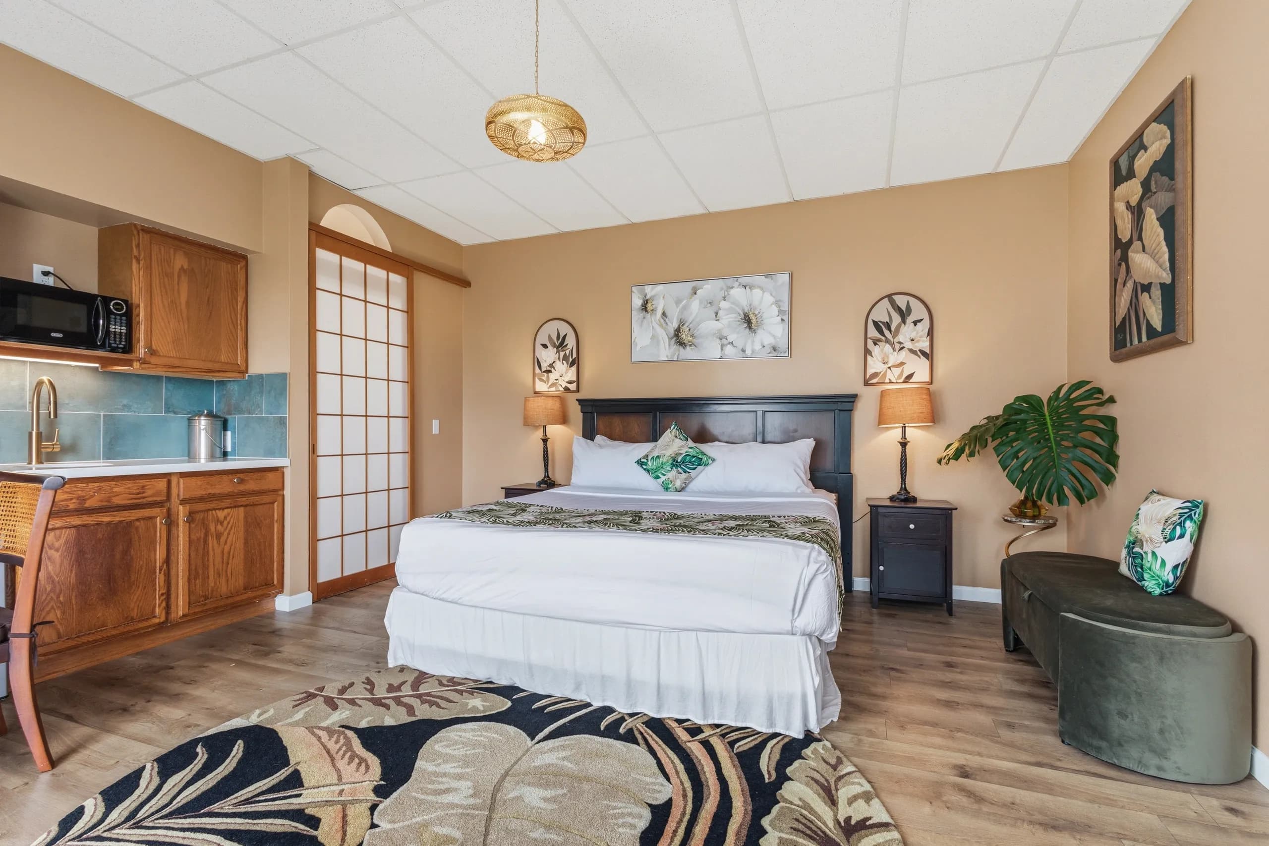 Cozy hotel room featuring a king-sized bed, kitchenette, and decorative accents.