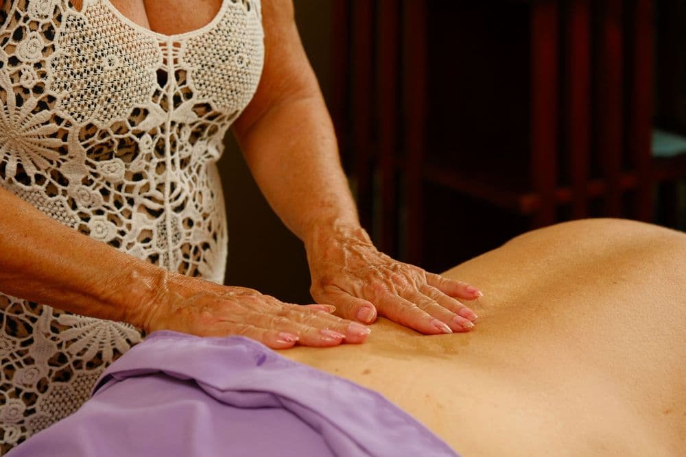 A person giving a massage to another individual, with hands positioned on the back.