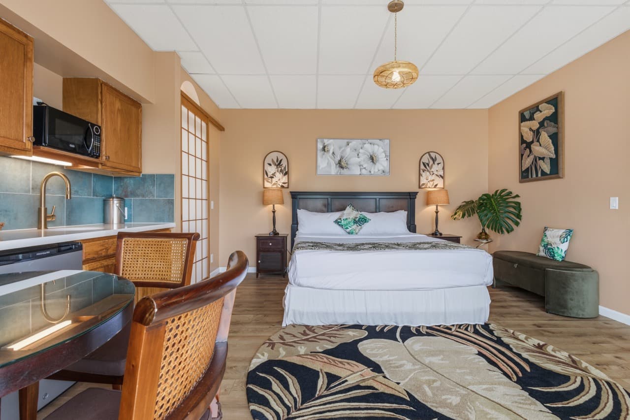 Cozy bedroom with a king-size bed, kitchenette, and tropical decor accents.