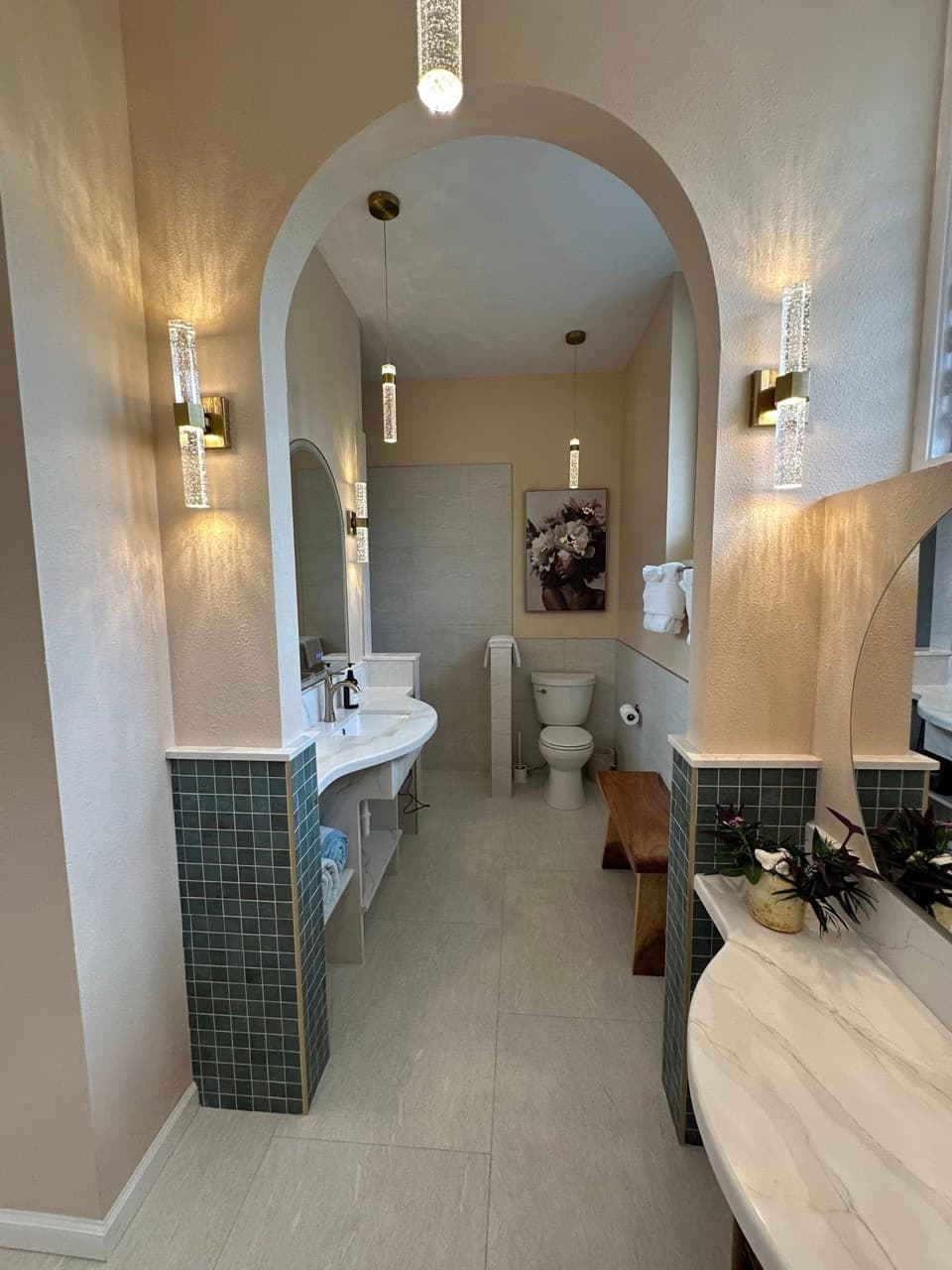 Modern bathroom featuring an arched entrance, elegant lighting, and a combination of light tiles and green accents.