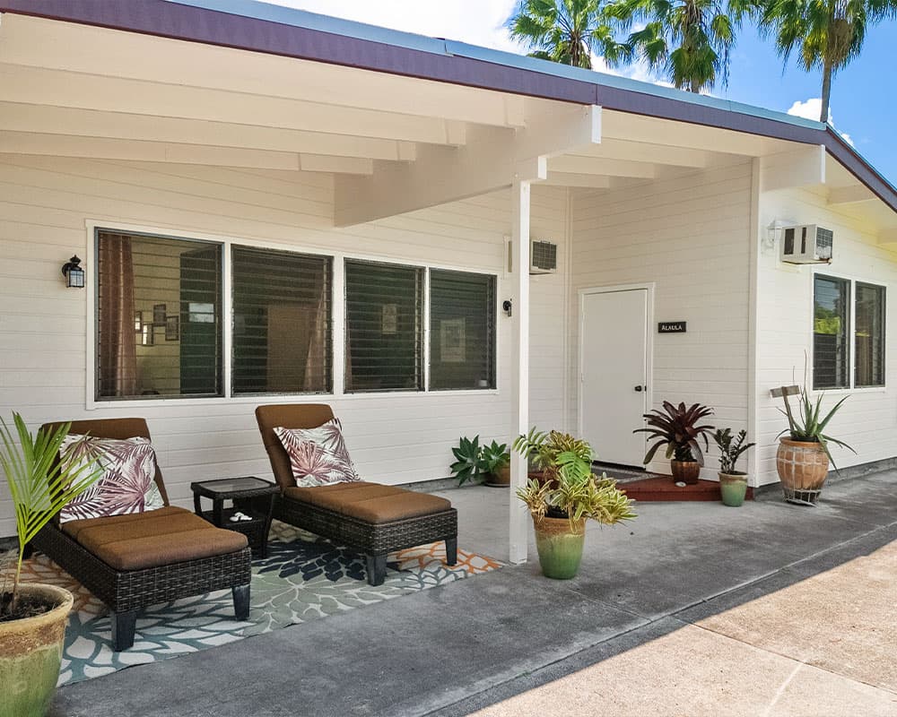 A modern porch features two lounge chairs, potted plants, and a welcoming entrance.