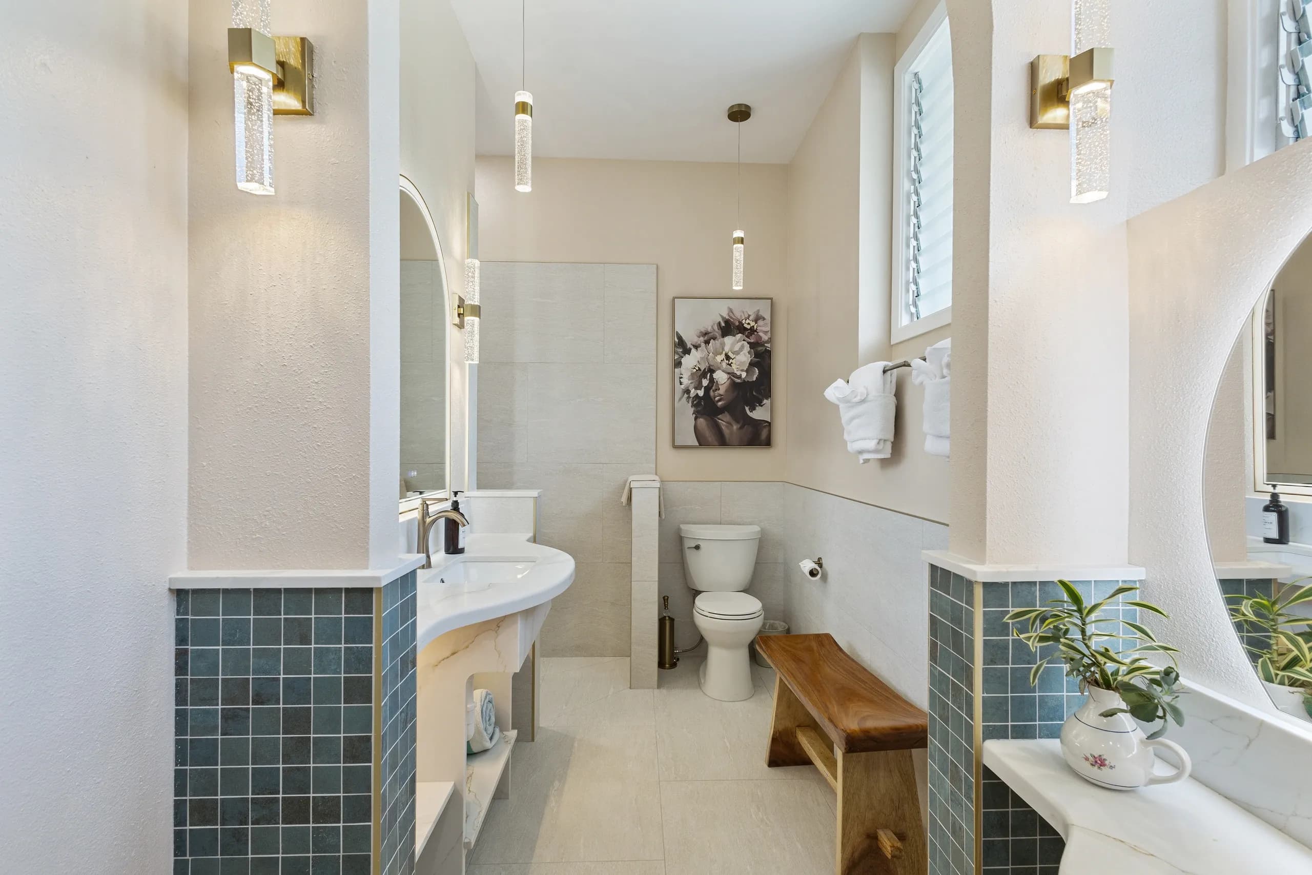 Modern bathroom featuring a circular mirror, white fixtures, blue tiled accents, and a wooden bench.