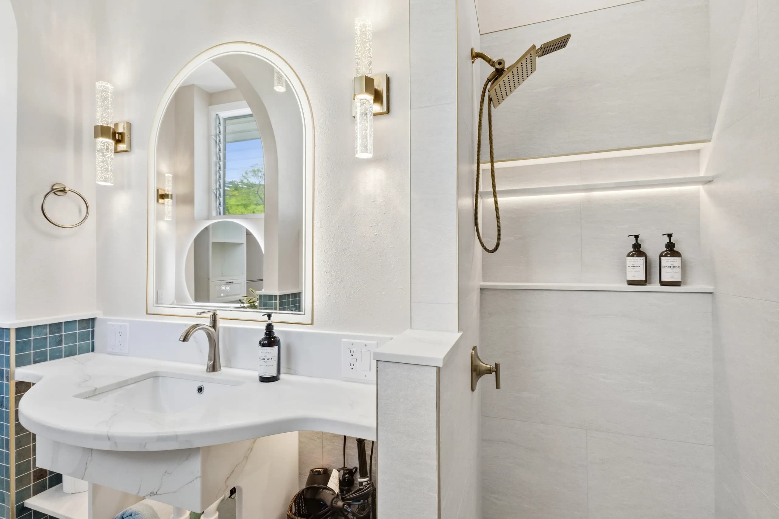A modern bathroom featuring a marble sink, a shower with a rainfall showerhead, and stylish lighting.