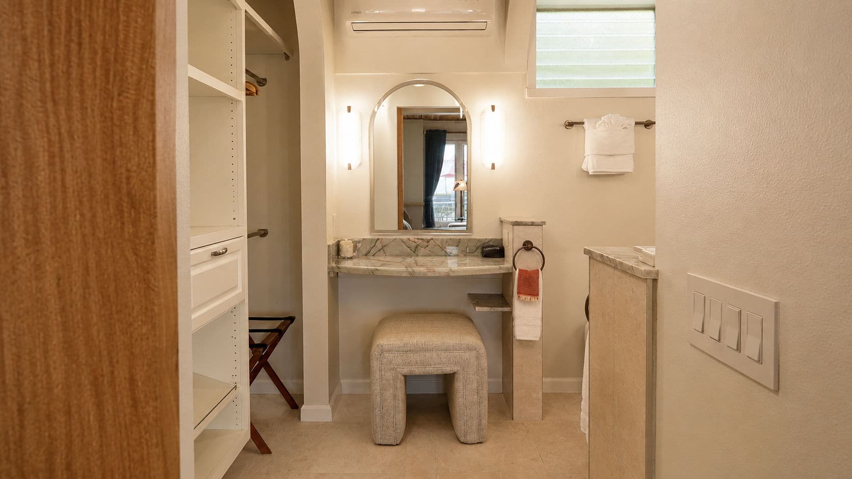 Modern bathroom featuring a vanity with a mirror, stool, and open shelving.