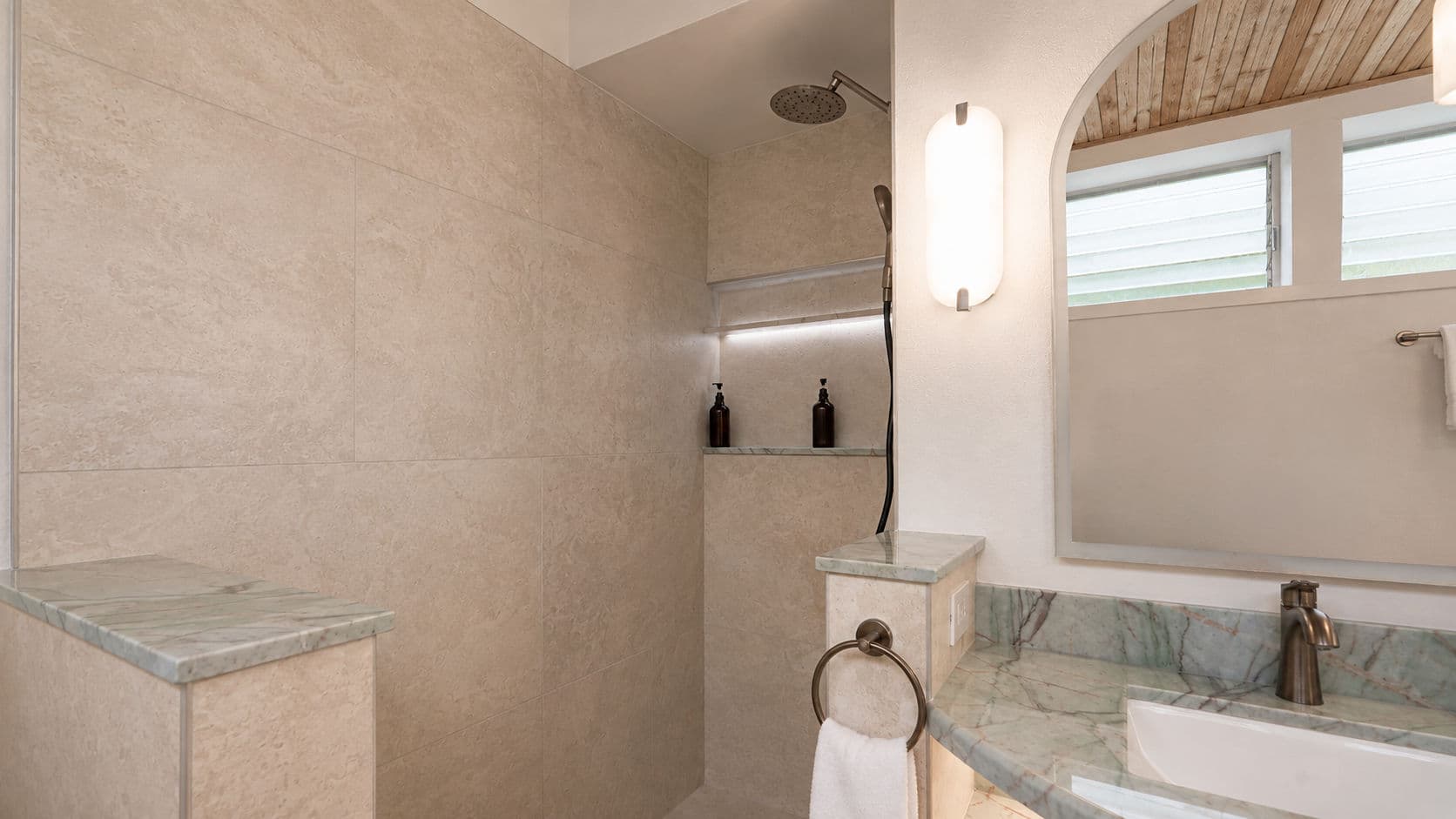 Modern bathroom featuring a walk-in shower with stone walls and green marble accents.
