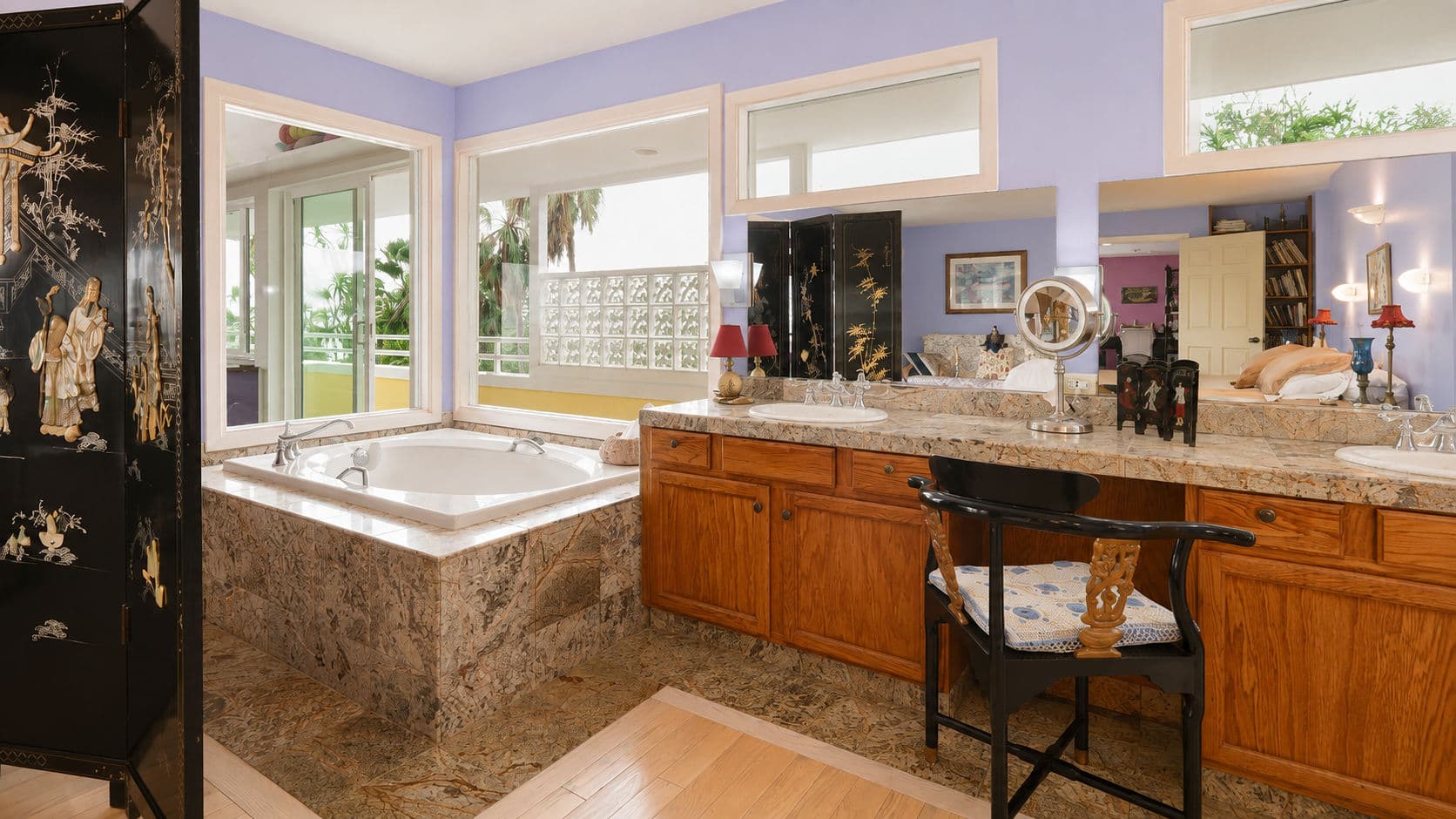 A modern bathroom with a jacuzzi, granite countertops, and large windows showcasing a bright, airy atmosphere.