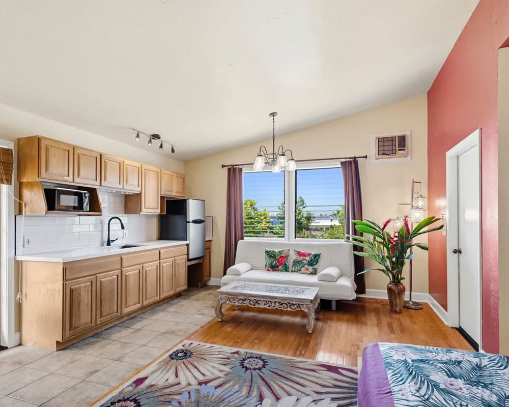 A bright, airy living space featuring a kitchen area, seating, and large windows with a view.