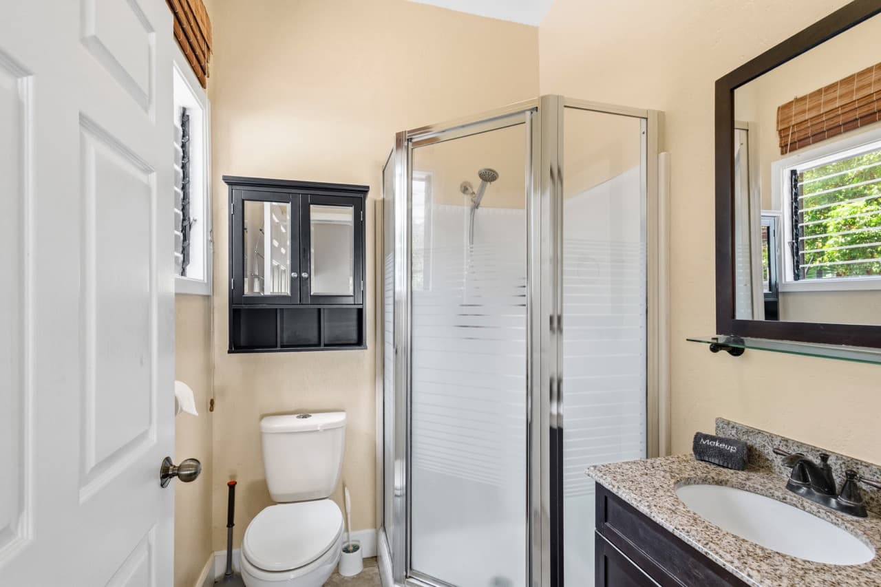 A modern bathroom featuring a glass shower, toilet, and granite countertop sink.