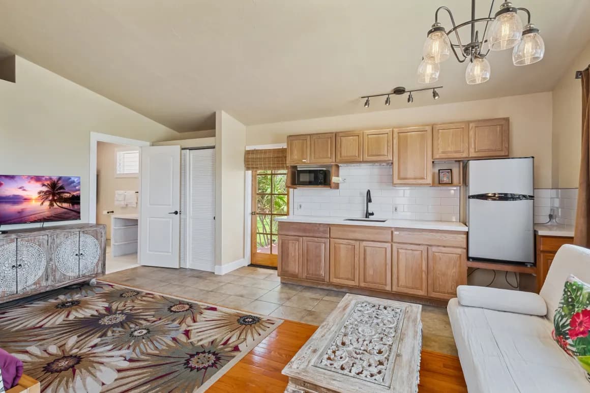 Bright kitchen and living area with wooden cabinets, a refrigerator, and stylish decor.