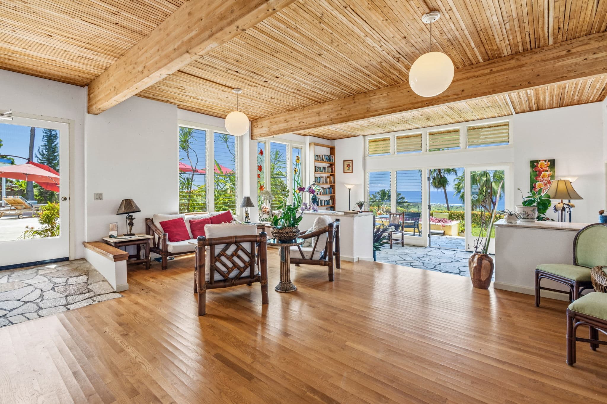 A bright, airy living space with wooden ceilings, large windows, and tropical views.